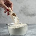 Woman hand holding spoon on top of flour bowl